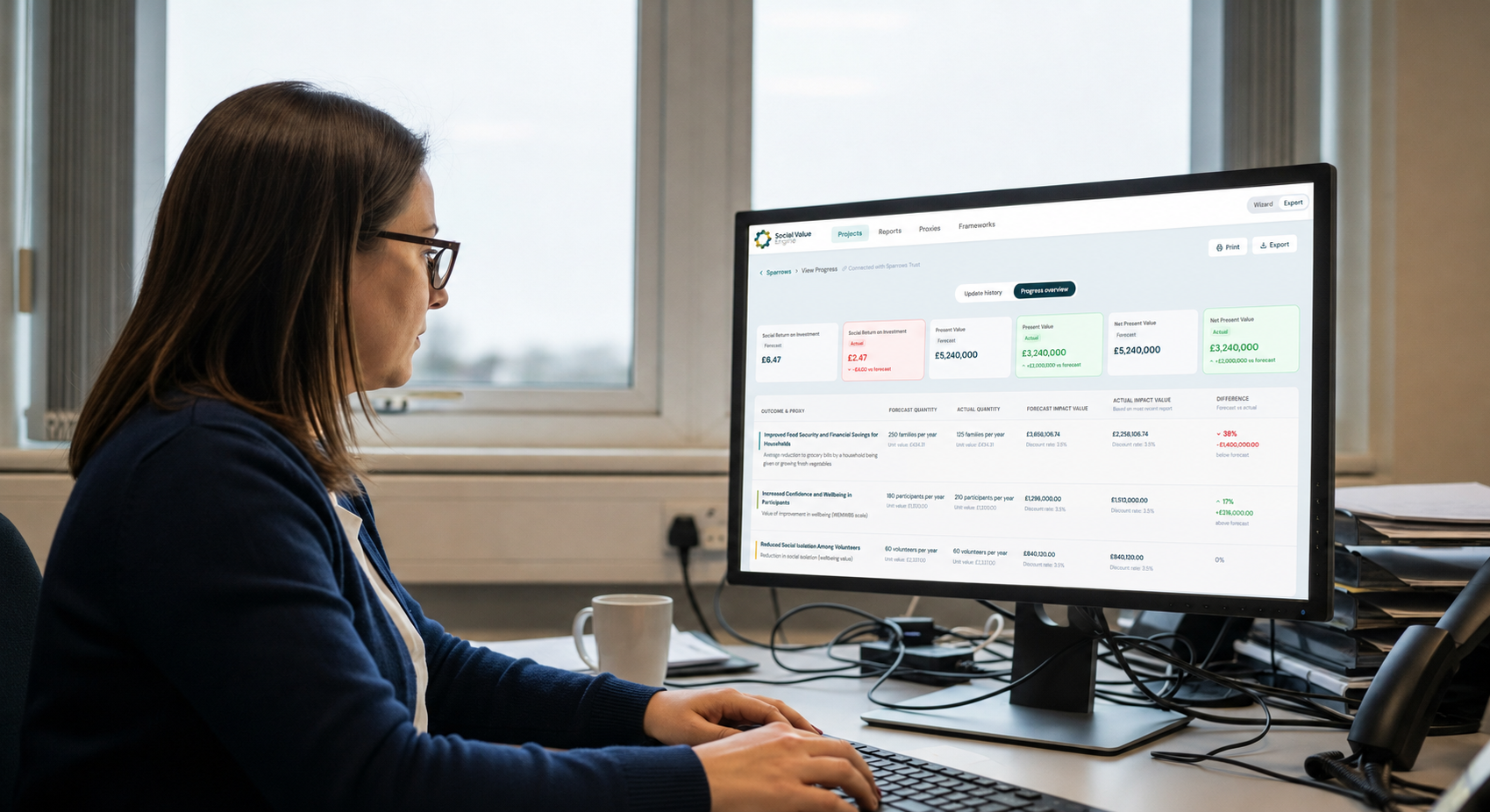 A public sector professional reviews contract portfolio data on dual monitors in a UK local authority office, illustrating the kind of commissioning and procurement oversight SVE Connect is designed to support